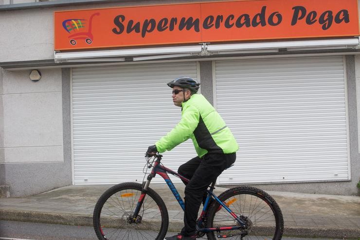 Un ciclista pasa fronte a un supermercado pechado por mor da pandemia de covid-19 en Paraleda, Lugo, a 19 de marzo de 2021 / Carlos Castro - Europa Press - Arquivo.