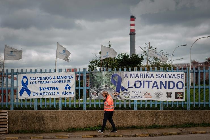 Unha persoa pasa diante dunha pancarta, colocada polos traballadores no valo da fábrica de Alcoa en San Cibrao 
