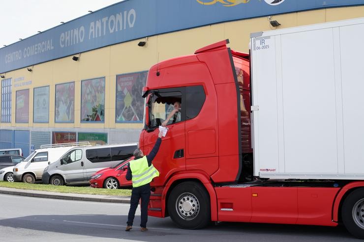 Un home entrega un papel a un transportista durante unha folga indefinida do transporte de mercadorías, no Polígono do Ceao, a 14 de marzo de 2022 