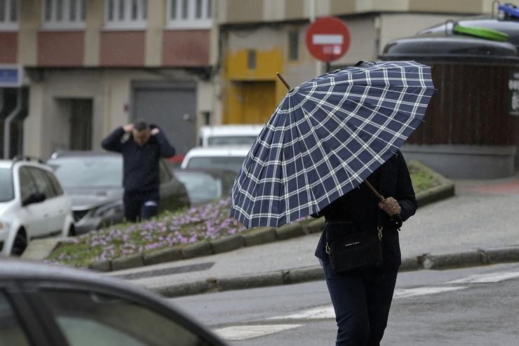 Unha persoa con paraugas camiña polo centro da Coruña, a 19 de xuño de 2022 