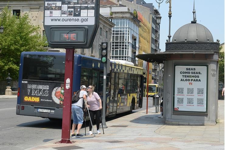 Dúas persoas saúdanse á beira dun termómetro na rúa que marca 41 graos, a 12 de xullo de 2022, en Ourens 