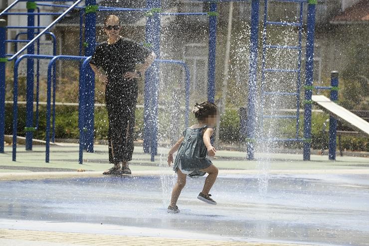 Dúas persoas refréscanse nuns chorros durante un día da onda de calor.. Rosa Veiga - Europa Press 