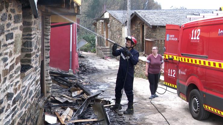 Un bombeiro arrefría unha vivenda arrasada polo lume en Alixo, O Barco de Valdeorras (Ourense). / Europa Press