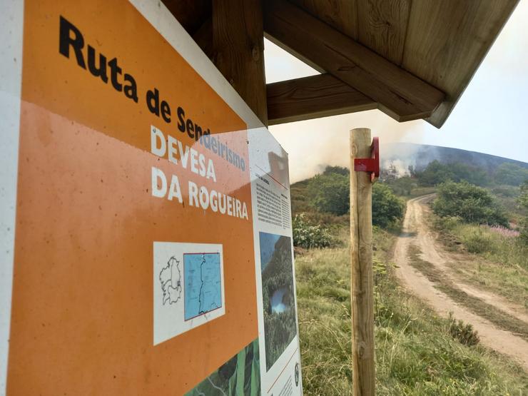 Letreiro co roteiro á Devesa da Rogueira. Detrás, xa no fume, a Lagoa de Lucenza 