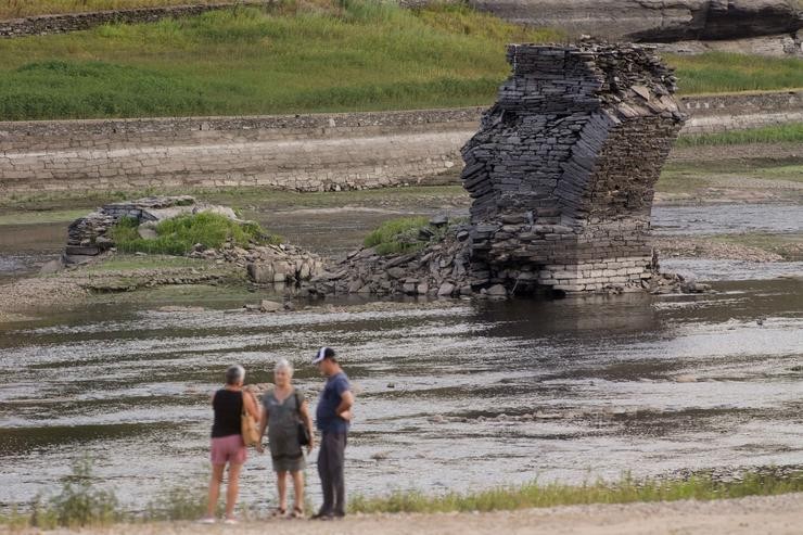 Tres persoas xunto ao río Miño, cuxo baixo caudal deixou á vista as ruínas do antigo Portomarín, que nos anos 60 do século pasado foi alagado polo encoro de Belesar, en Escairón, a 9 de agosto de 2022, en Escairón, Lugo, Galicia (España). L. Carlos Castro - Europa Press / Europa Press