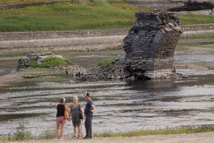 Tres persoas xunto ao río Miño, cuxo baixo caudal deixou á vista as ruínas do antigo Portomarín, que nos anos 60 do século pasado foi alagado polo encoro de Belesar, en Escairón, a 9 de agosto de 2022, en Escairón, Lugo, Galicia (España). L. Carlos Castro - Europa Press 