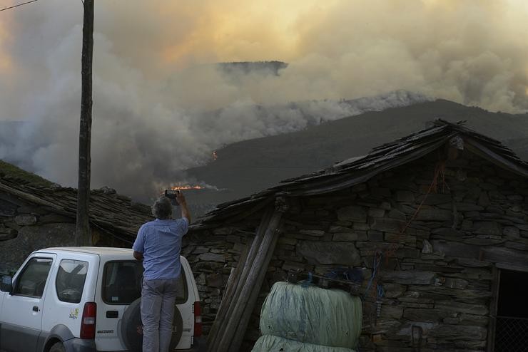 Un home fotografa as chamas do incendio forestal, a 10 de agosto de 2022, en Laza 