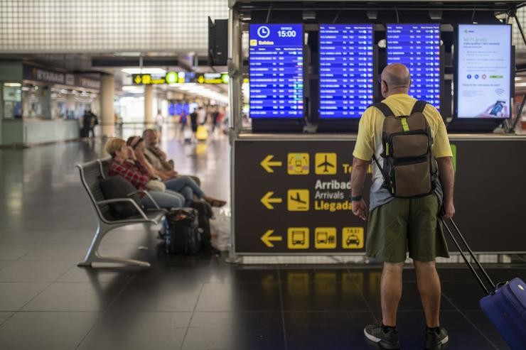 Un home mira un panel de chegadas e saídas nun aeroporto 