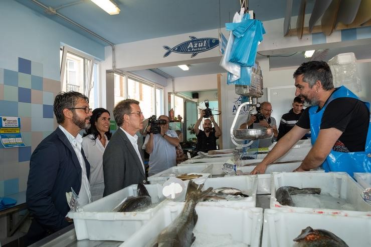 O presidente do Partido Popular, Alberto Núñez Feijóo, charla cun pescadero durante a súa visita a Porto do Son.. César Arxina - Europa Press 