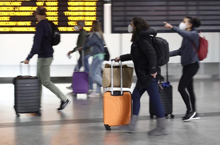Arquivo - Varias persoas, con maletas, pasan xunto a un panel de saídas con diferentes destinos en Atocha. Eduardo Parra - Europa Press - Arquivo / Europa Press