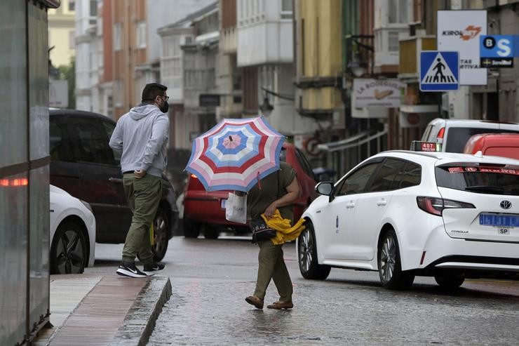  Unha muller resgárdase do vento e a choiva cun paraugas no centro da cidade na Coruña / Europa Press