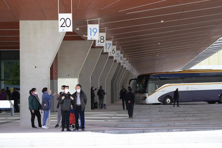 Varias persoas esperan autobuses desde unha das dársenas da nova estación de autobuses de Santiago de Compostela 