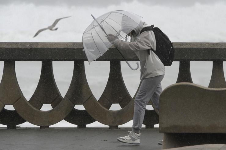 Unha persoa protéxese da choiva e o vento cun paraugas, a 20 de outubro de 2023, na Coruña 