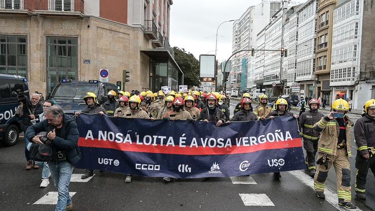 Bombeiros dos parques comarcais suxeitan unha pancarta durante unha concentración fronte á Deputación da Coruña / M. Dylan
