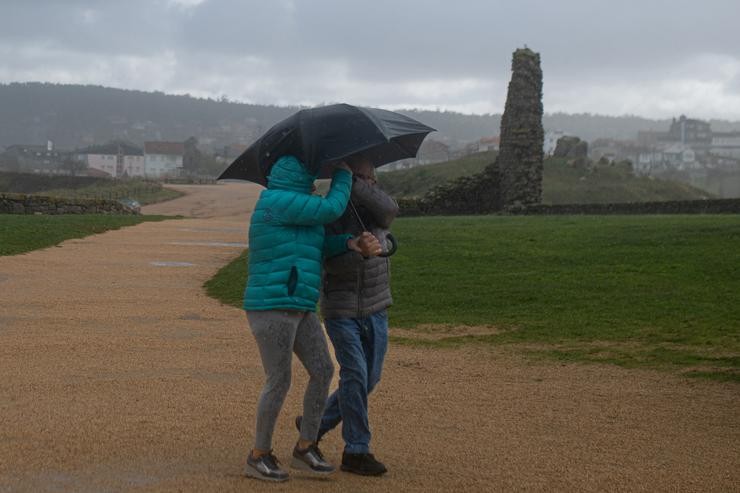 Dúas persoas protéxense da choiva cun paraugas, na praia da Lanzada, a 5 de novembro de 2023, no Grove, Pontevedra, Galicia (España). A borrasca Domingos deixou en toda Galicia un total de 1.166 incidencias. En Pontevedra, foron 438, l. Elena Fernández - Europa Press 