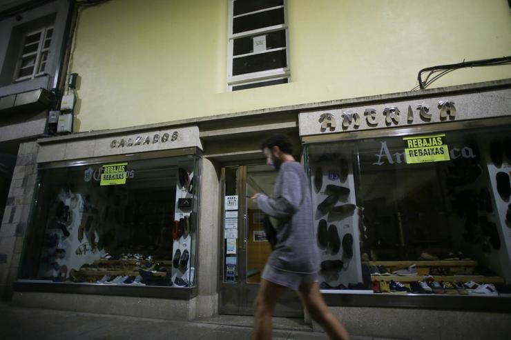 Unha persoa camiña á beira dunha tenda de roupa sen iluminación./ Carlos Castro - Europa Press - Arquivo / Europa Press