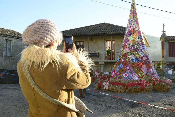 Unha persoa toma unha fotografa fronte á árbore de Nadal feito con ganchillo, a 18 de decembro de 2023, en Ousende, Paderne 