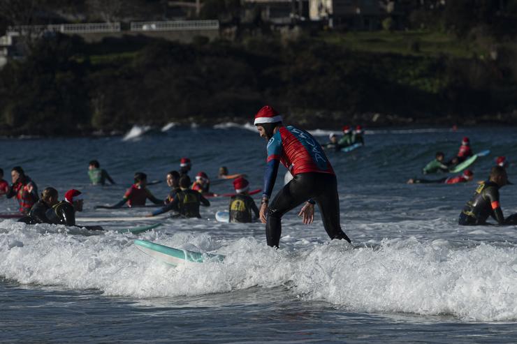 Un home disfrazado de Papá Noel surfea./ Adrián Irago - Europa Press / Europa Press