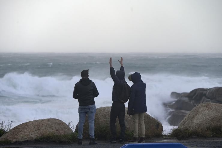 Tres novos miran e fotografan o mar embravecido, a 4 de novembro de 2023, na Coruña 