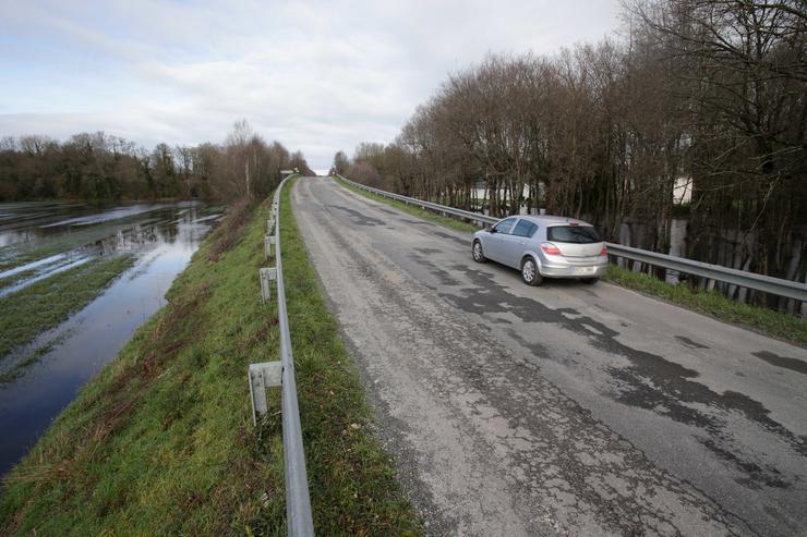 Un coche pasa á beira de vexetación afectada polo desbordamento do río Miño ao seu paso por Triabá, a 3 de xaneiro de 2023, en Castro de Rei /  Carlos Castro - Europa Press /