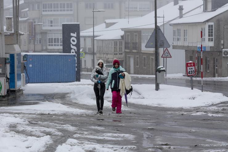 Dúas mulleres camiñan co seu can por unha rúa cuberta de neve, a 26 de xaneiro de 2023, en Pedrafita do Cebreiro, Lugo, Galicia.. Carlos Castro - Europa Press / Europa Press