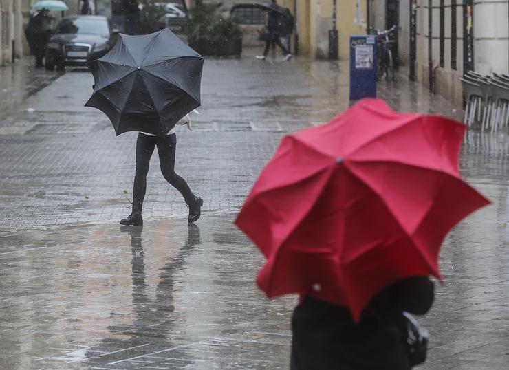 Dúas persoas sosteñen paraugas como consecuencia da choiva, a 6 de febreiro de 2023, en Valencia 