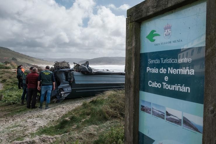 Membros da Garda Civil observan o interior da planadora varada na praia de Nemiña 