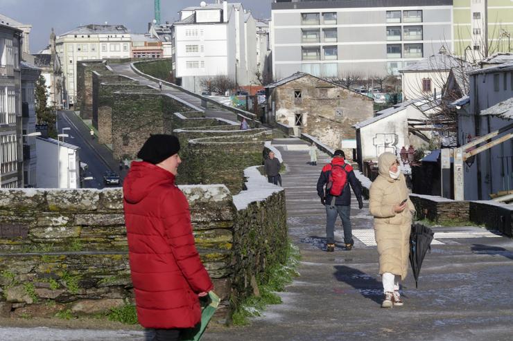 Arquivo - Varias persoas pasean sobre unha lixeira capa de neve na muralla romana de Lugo, a 18 de xaneiro de 2023, en Lugo, Galicia (España). A cota de neve está en 400 metros e foi acompañada por un descenso das temperaturas. A situación máis. Carlos Castro - Europa Press - Arquivo / Europa Press