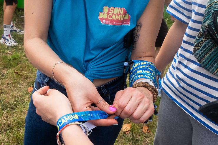 Unha moza pon unha pulseira na zona de acampada no festival O son de Camiño, no Monte do Gozo, a 15 de xuño de 2022, en Santiago de Compostela / César Arxina - Arquivo