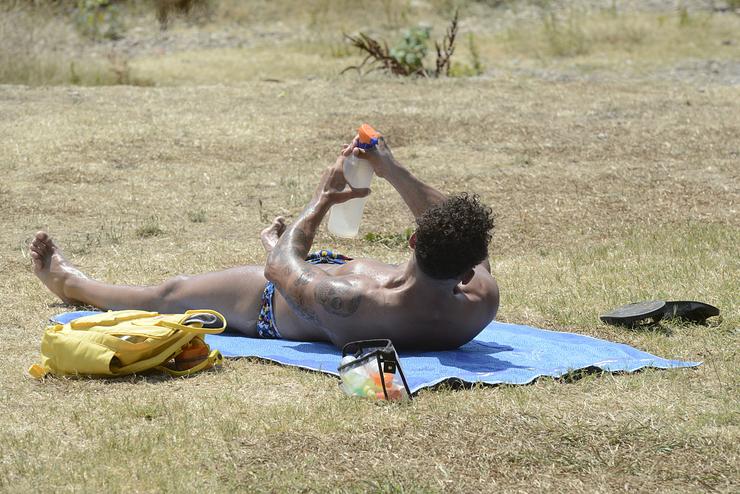 Un home toma o sol na zona piscinas de Oira, a 12 de xullo de 2022, en Ourense 