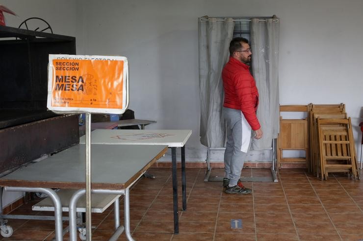 Unha persoa xunto a unha cabina electoral exerce o seu dereito a voto na mesa electoral do local parroquial de Recelle, nunha mesa que agrupa a varias aldeas da contorna, a 28 de maio de 2023, en Portomarín / Carlos Castro - Europa Press - Arquivo