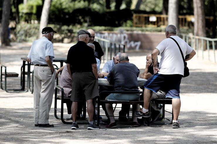 Varios pensionistas e xubiliados xogan ao dominou nun parque  