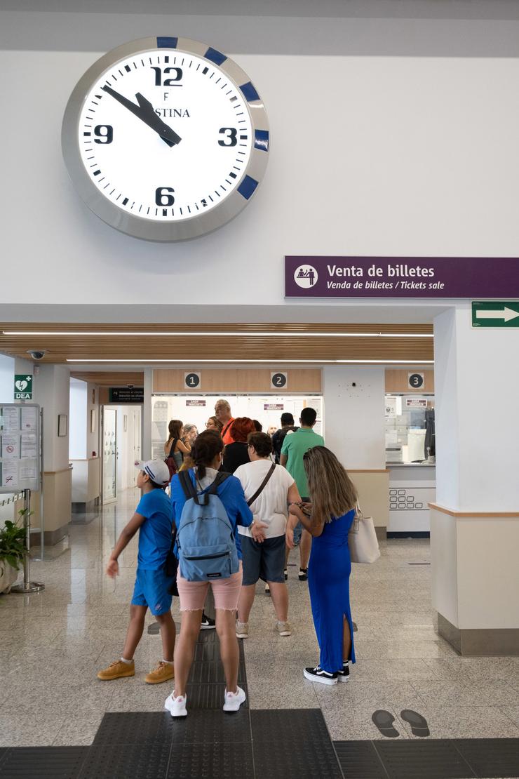 Varias persoas fan cola para adquirir un abono gratuíto na estación de trens na estación de Santiago 