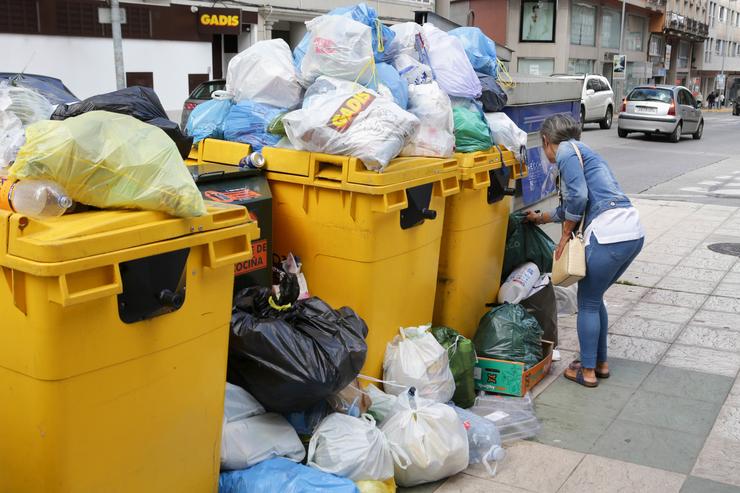 Unha muller deposita unha bolsa de lixo á beira de colectores de lixo desbordados / Carlos Castro - Europa Press - Arquivo