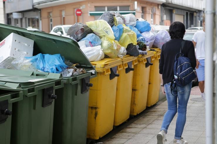 Unha muller camiña á beira de colectores de lixo desbordados durante a cuarta semana da folga na recollida de lixo de Vilalba, a 11 de setembro de 2023 / Carlos Castro - Europa Press - Arquivo