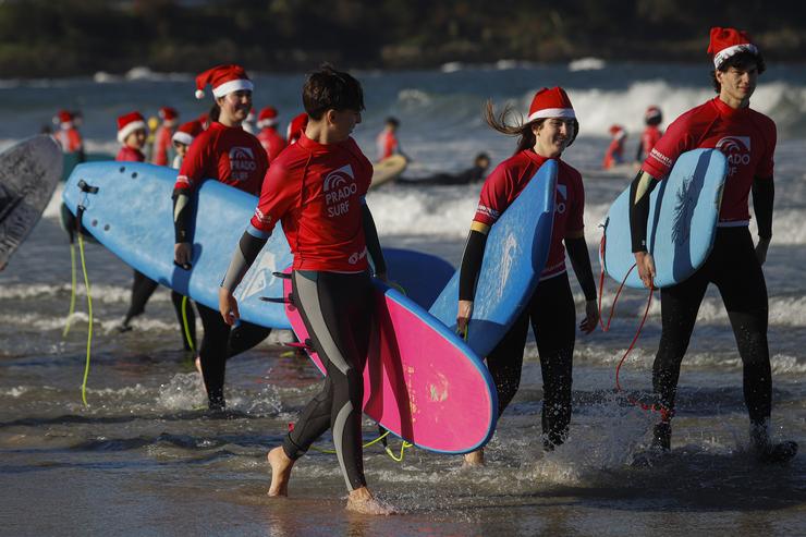 Decenas de persoas disfrazadas de Papá Noel surfean durante a Papanoelada Surfera, na praia de Patos.. Adrián Irago - Europa Press 
