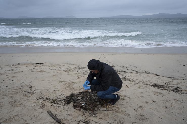 Un voluntario recolle pélets na praia de Samil. Adrián Irago - Europa Press 