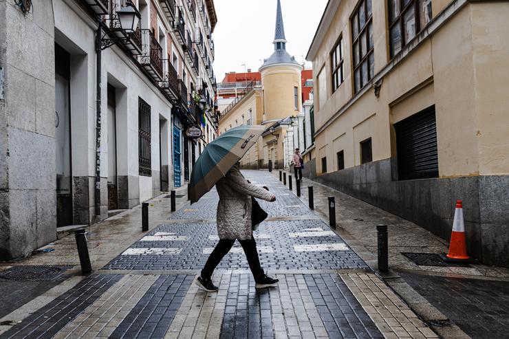 Unha muller protéxese da choiva cun paraugas, a 2 de novembro de 2023, en Madrid 