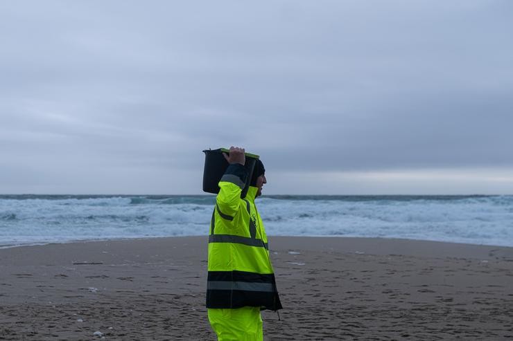 Un home carga un cubo cheo de pellets, na praia Do Dique, a 13 de xaneiro de 2024, en Queiruga, A Coruña, Galicia (España). A coñecida xa como a ?marea branca?, prevese que proceda do seis colectores do buque Toconao que caeron ao mar en ag. Elena Fernández - Europa Press 