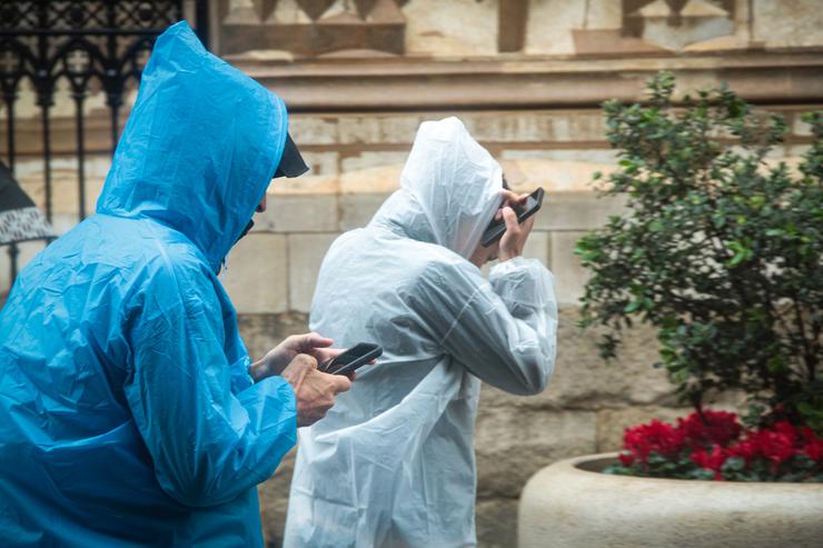 Dúas persoas protéxense da choiva cun impermeable / María José López - Arquivo