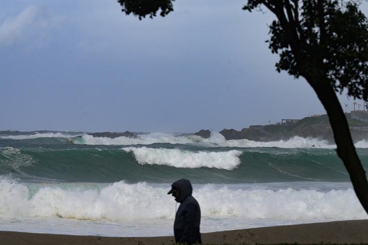 Unha persoa camiña diante das ondas durante a fronte meteorolóxica, a 23 de febreiro de 2024, na Coruña, Galicia (España).. M. Dylan - Europa Press / Europa Press