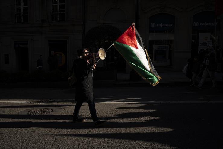 Unha persoa con bandeira palestina e un altofalante, durante unha manifestación en apoio a Palestina 