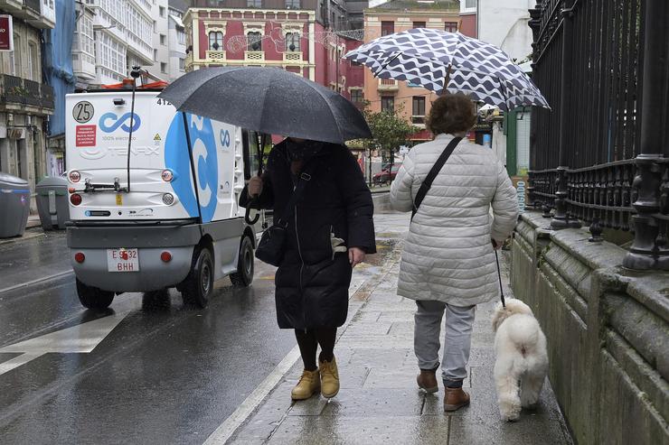 Dúas persoas refúxianse do vento con paraugas na Coruña / M. Dylan - Arquivo