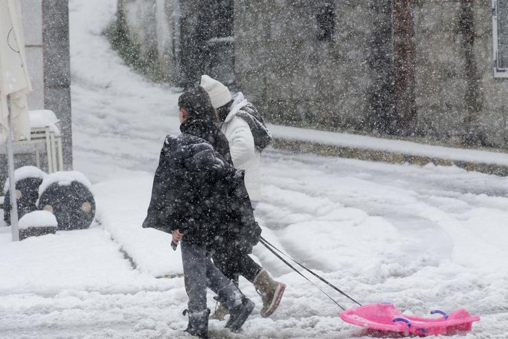 Dúas persoas camiñan cun trineo pola neve, a 18 de xaneiro de 2023, en Castroverde, Lugo 