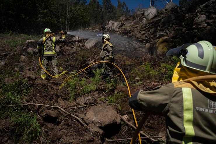 Axentes dos equipos de bombeiros traballan no lugar do incendio, a 16 de abril de 2024, en Crecente 