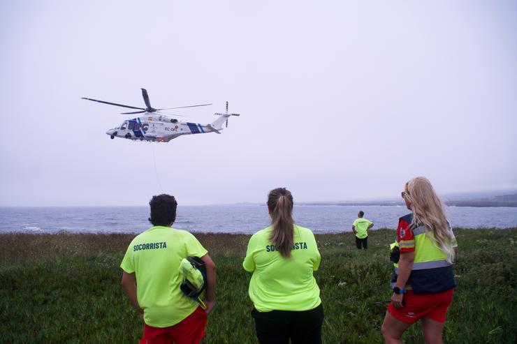 Varios socorristas observan a un helicóptero rescatando a un home novo na Punta do Castro, a 28 de xullo de 2024, en San Pedro de Benquerencia, Barreiros, Lugo, Galicia.. Gustavo da Paz - Europa Press / Europa Press