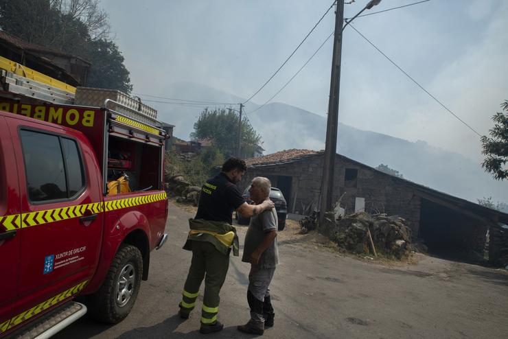 Un residente e un bombeiro despois da noite co lume ao redor da aldea, a 10 de agosto de 2025, en Maceda 