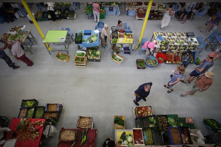 Varias persoas compran alimentos nun mercado 