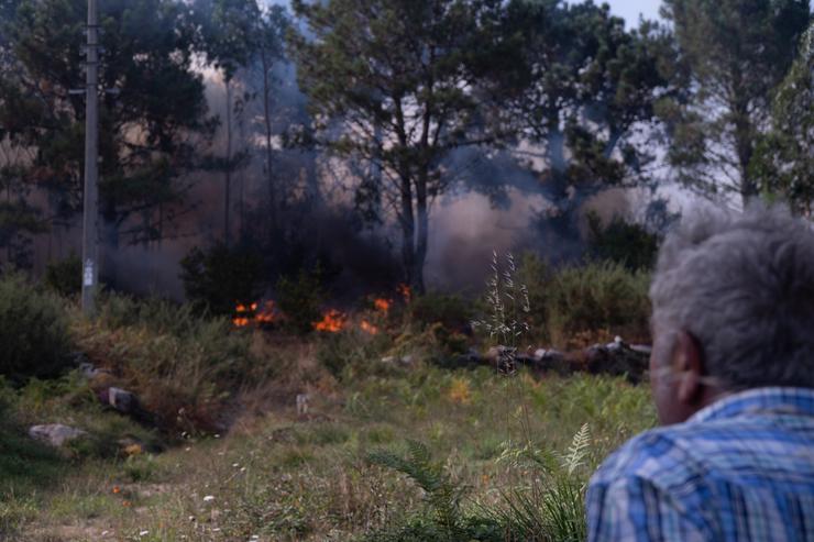 Unha persoa observa o lume, a 5 de agosto de 2025, en Ponteceso, A Coruña, Galicia (España). Un novo incendio no municipio coruñés de Ponteceso obrigou este martes a desaloxar a veciños da parroquia de Corme Aldea.. Gustavo da Paz - Europa Press 
